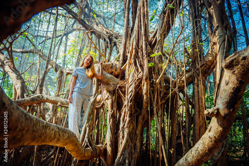 young woman posing on banyan banjan tree during vocation in india goa photo