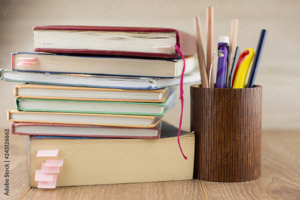 attainment of knowledge: a pile of books with bookmarks, glasses and pencils in a pencil stand attainment of knowledge: a pile of books with bookmarks, glasses and pencils in a pencil stand