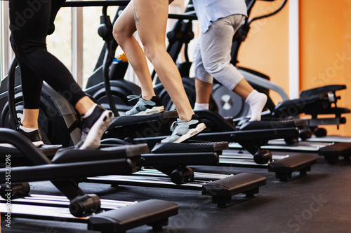 Attractive young people working out on an elliptical trainer in gym. The concept of volitional discipline and endurance. photo