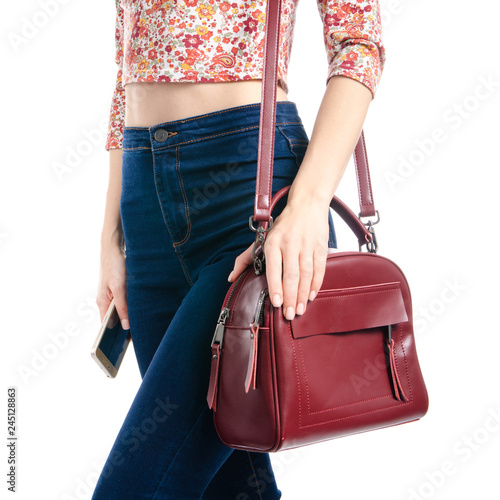 Woman in blue jeans and shirt red bag smartphone in hand macro on white background isolation