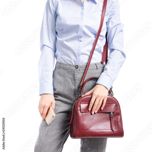 Woman in gray pants and blue shirt put smartphone in red bag macro on white background isolation