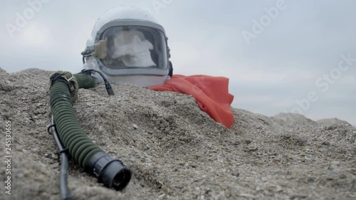 The head of a dead cosmonaut lies on the sand by the sea. Astronaut crashed on his spaceship. Cloudy weather, the wind blows