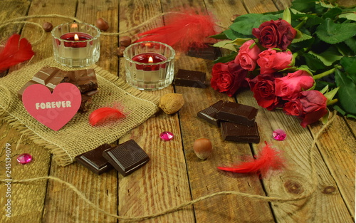 Valentine's Day, wooden background - a heart with the word "forever" with roses, chocolate and candles