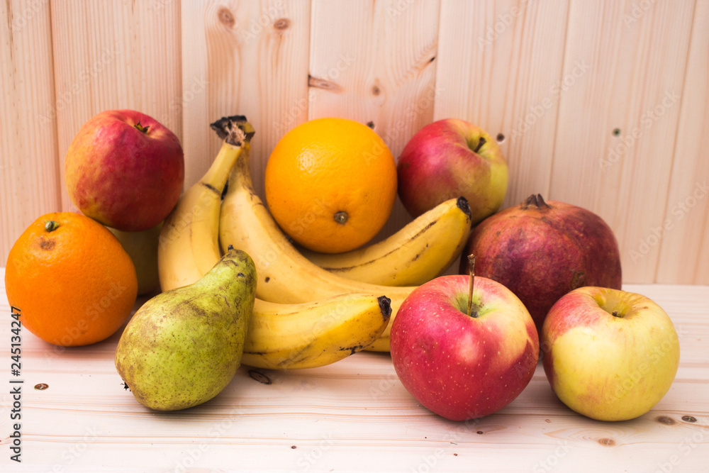 Various fruits apples, bananas, oranges, pomegranates on natural wooden background. Healthy food