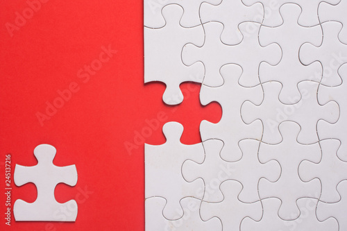 Incomplete white jigsaw puzzle pieces on red background