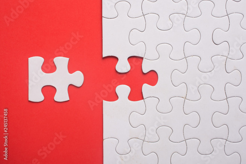 Incomplete white jigsaw puzzle pieces on red background