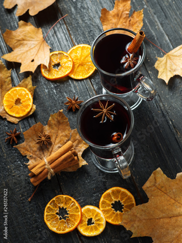 Mulled wine in a traditional glass glass glass on a wooden background with spices and orange