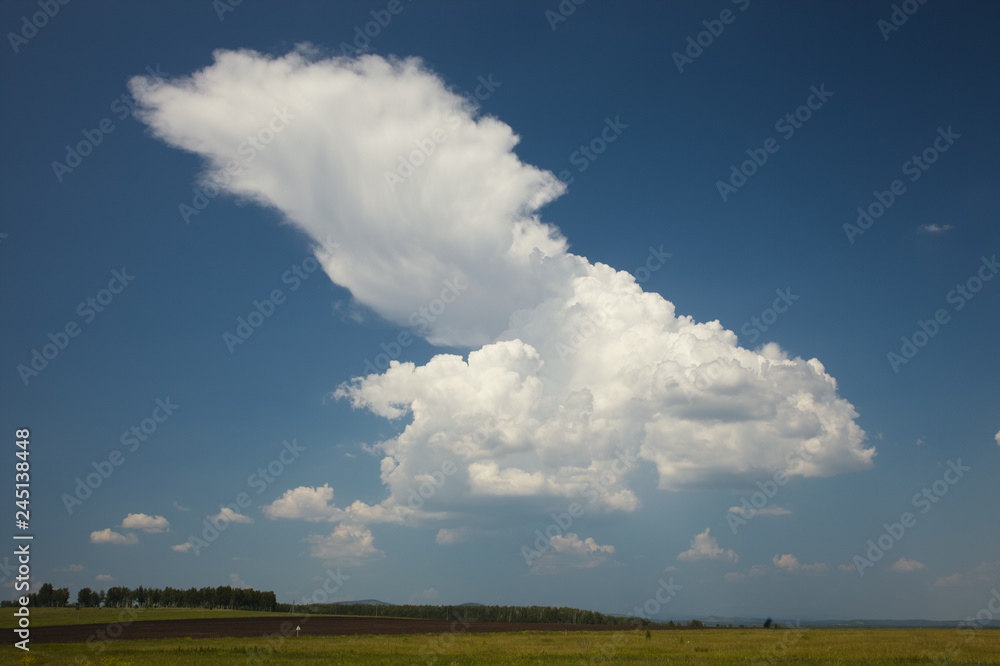The ascending stream of a thunderstorm cloud over a field in the countryside.