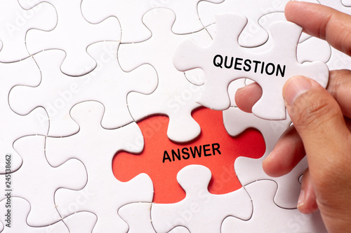 Hand holding piece of jigsaw puzzle with word question & answer