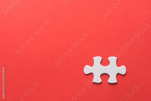 Unfinished white jigsaw puzzle pieces on red background