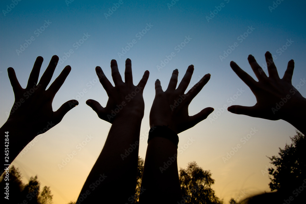 Open palms hands silhouettes against sunset blue sky