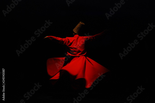 Whirling dervish in red garment on black background photo