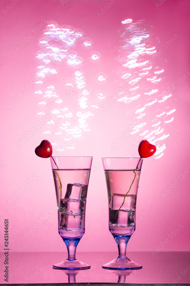 Two glasses with a cocktail and two hearts, Valentine's day concept.