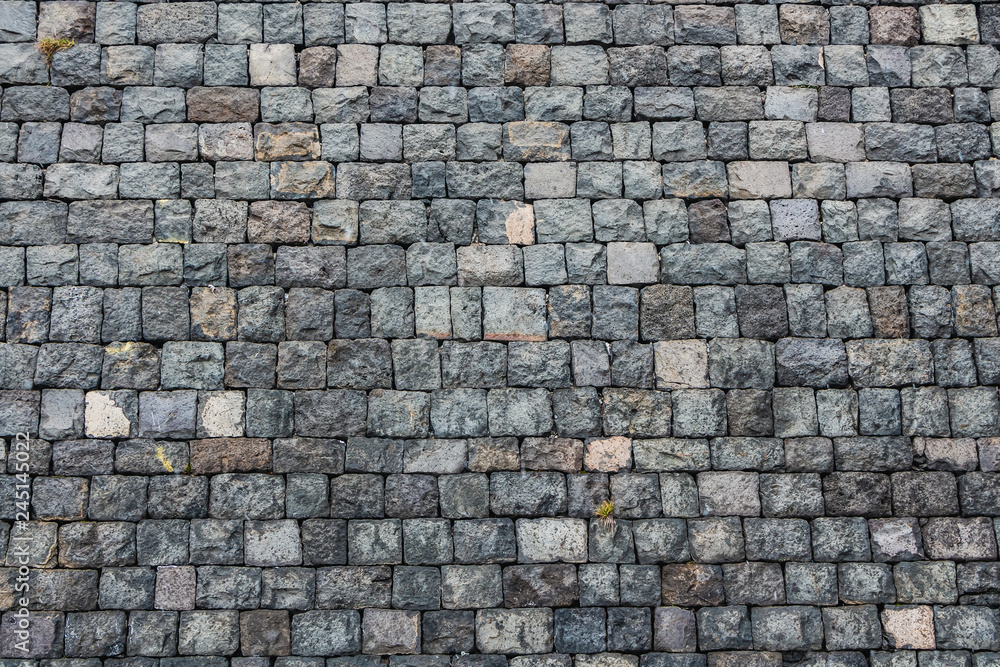 Fototapeta premium A beautiful horizontal texture of part of an old gray brick wall from frozen volcanic lava from Etna volcano in Sicily in Italy on the photo