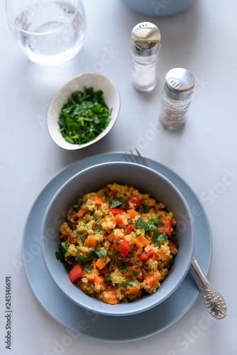 Healhty vegan bowl with quinoa, pumpkin, pepper and carrot on gray wooden background. Selective focus