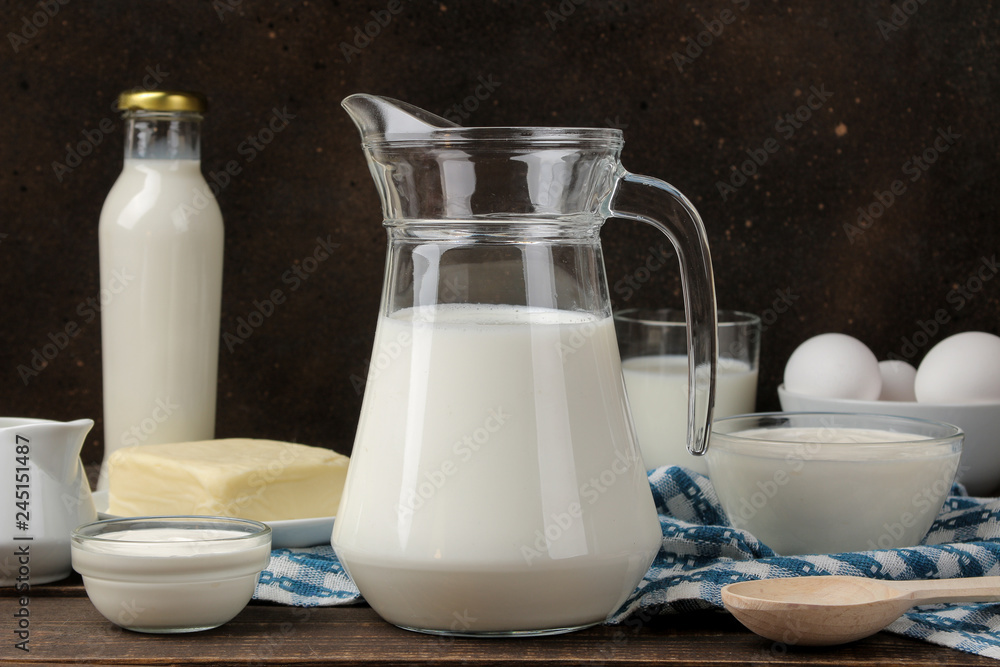 milk products. milk, sour cream, cheese, butter and cottage cheese on a brown wooden table milk products. milk, sour cream, cheese, butter and cottage cheese on a brown wooden table