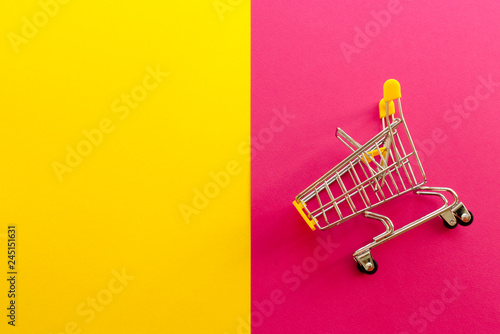empty shopping cart on pink and yellow background