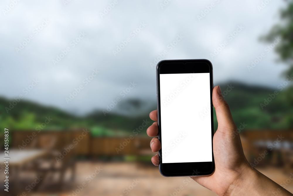 Hand that are holding a black phone with a blank white screen in the morning light of an air residence.