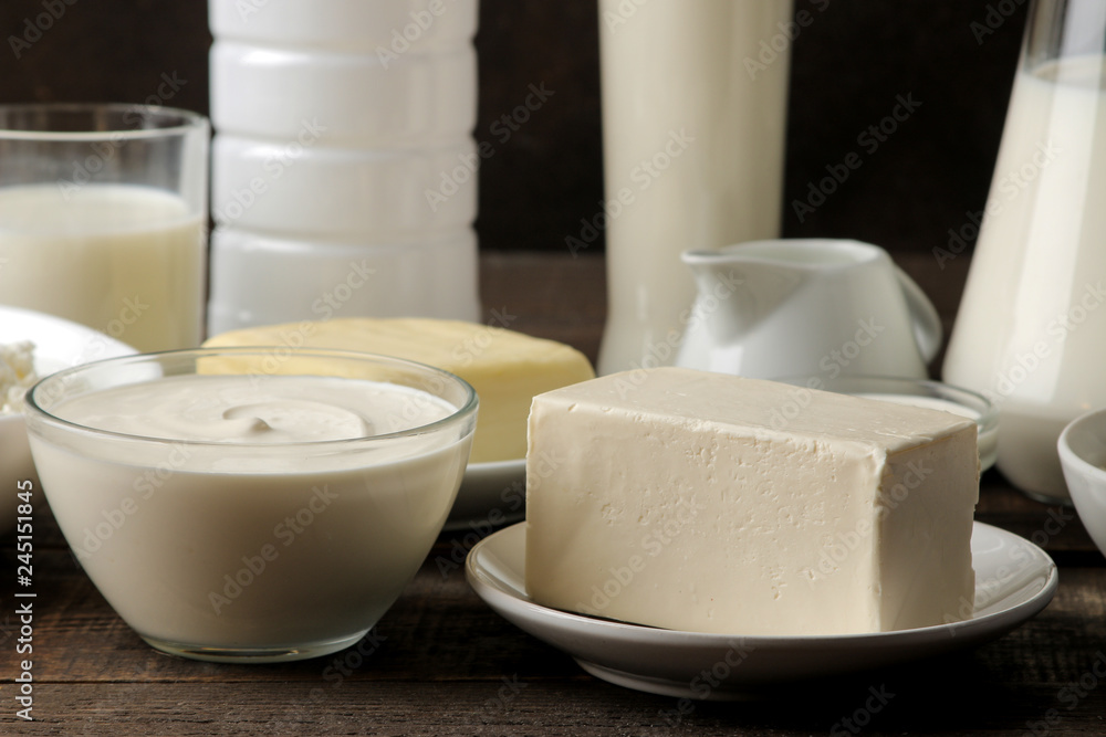 milk products. milk, sour cream, cheese, butter and cottage cheese on a brown wooden table milk products. milk, sour cream, cheese, butter and cottage cheese on a brown wooden table