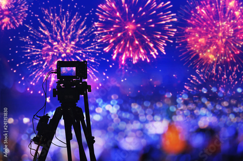 back side silhouette digital camera on tripod recording beautiful fireworks for celebrate in low light photo