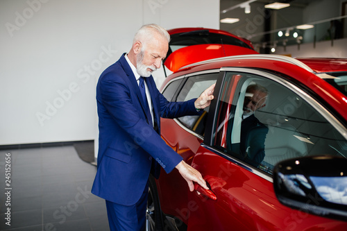 Senior man choosing a new car at car showroom.