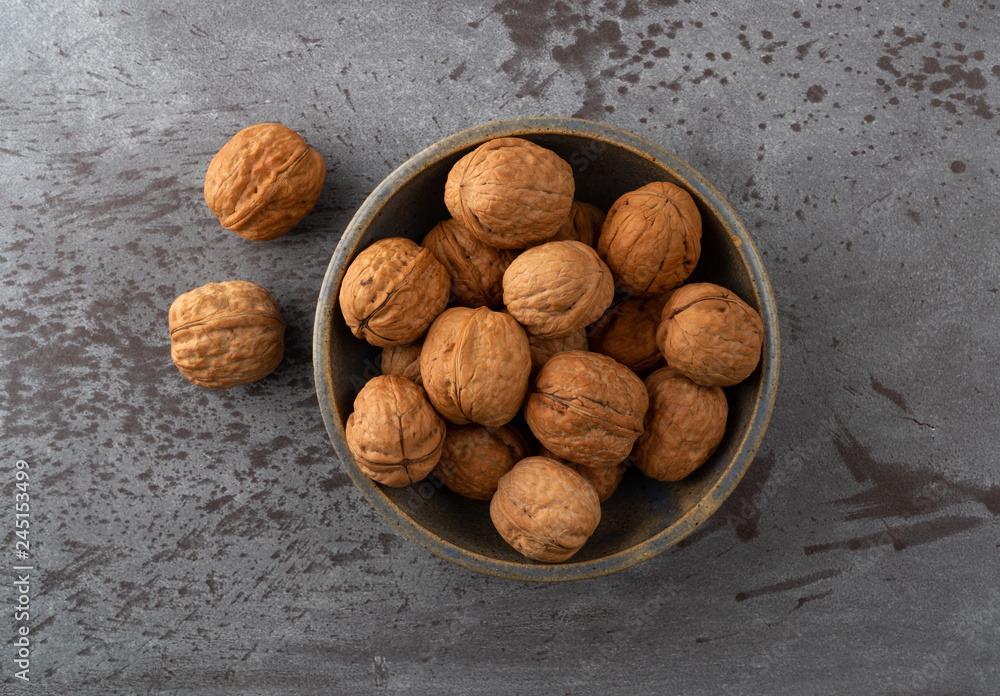 Bowl of walnuts with two to the side Bowl of walnuts with two to the side