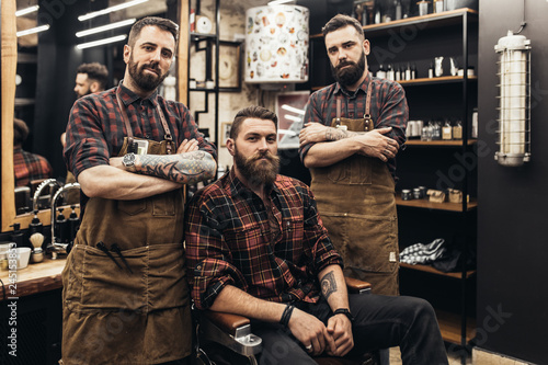 Hipster young good looking man at barber shop and hairstylist. Trendy and stylish beard styling and hair cut.