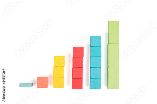 Toy wooden blocks as financial graph. Graph with four 4 steps. Growing chart. Infographic diagram  chart over grey or black or dark background. Multi-colored wooden blocks.