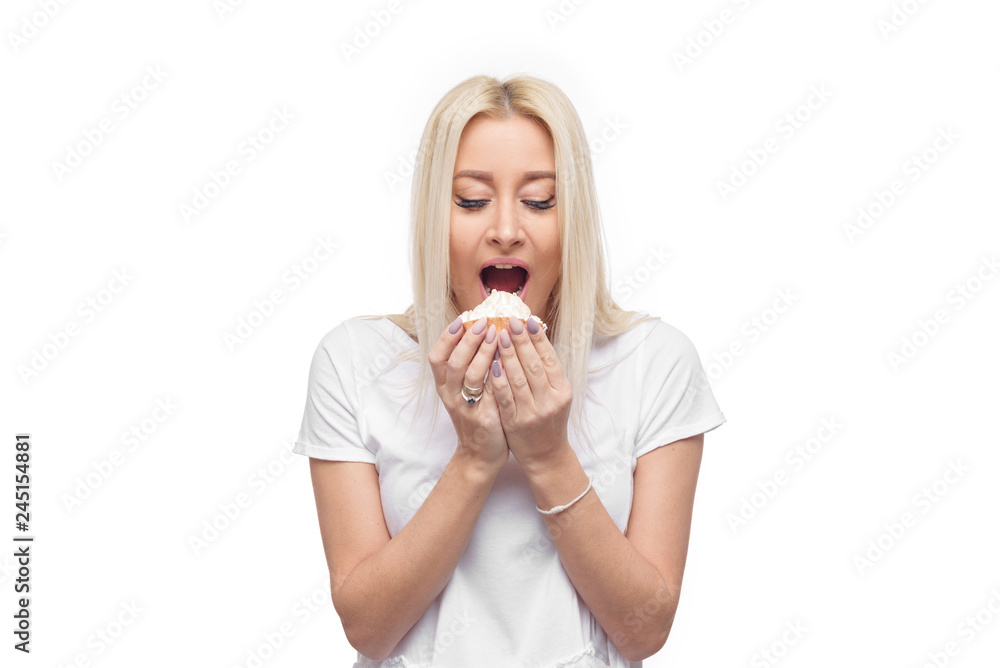 Diet. Dieting concept. Image of beautiful blond woman in white clothe isolated over white background holding and eating cake with pleasure Diet. Dieting concept. Image of beautiful blond woman in white clothe isolated over white background holding and eating cake with pleasure