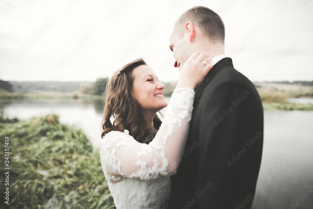 Romantic, fairytale, happy newlywed couple hugging and kissing in a park, trees in background Romantic, fairytale, happy newlywed couple hugging and kissing in a park, trees in background