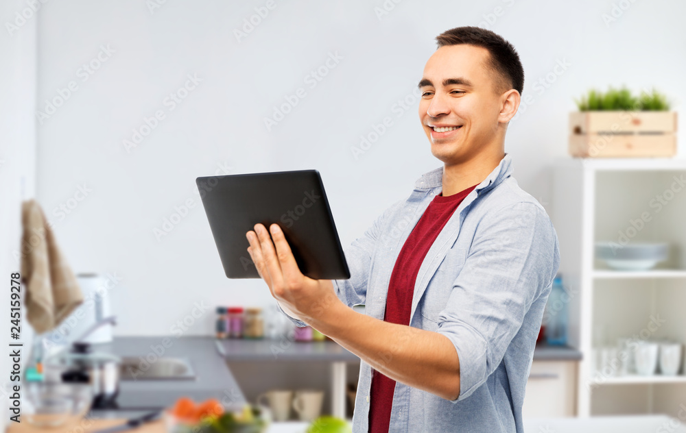 technology, cooking and people concept - happy young man tablet computer over kitchen background technology, cooking and people concept - happy young man tablet computer over kitchen background