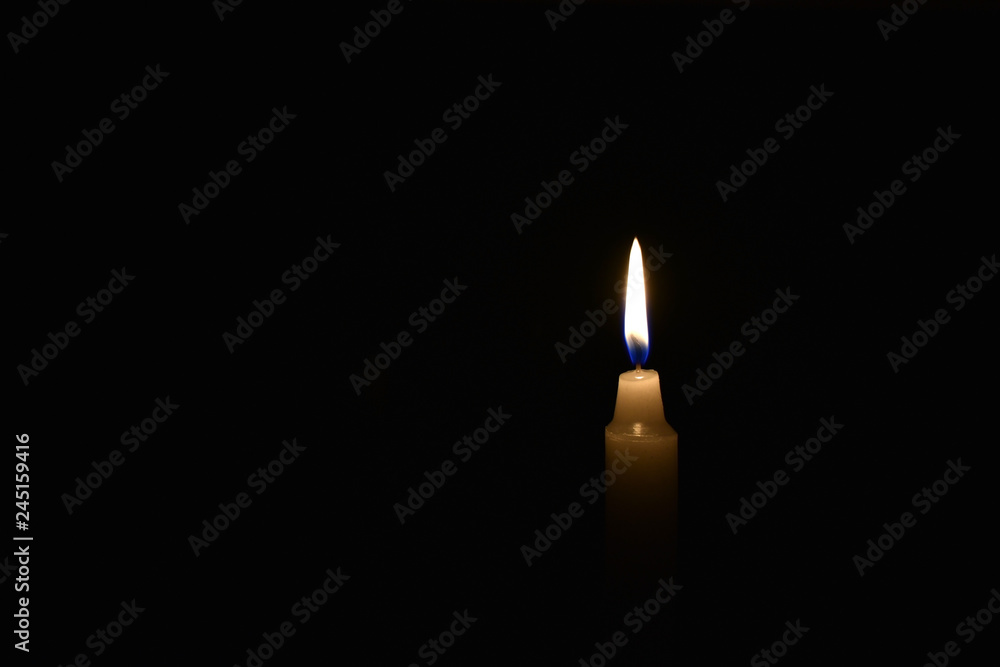 Candle burning in the black background. Located on the right side of the shot. Candle burning in the black background. Located on the right side of the shot.