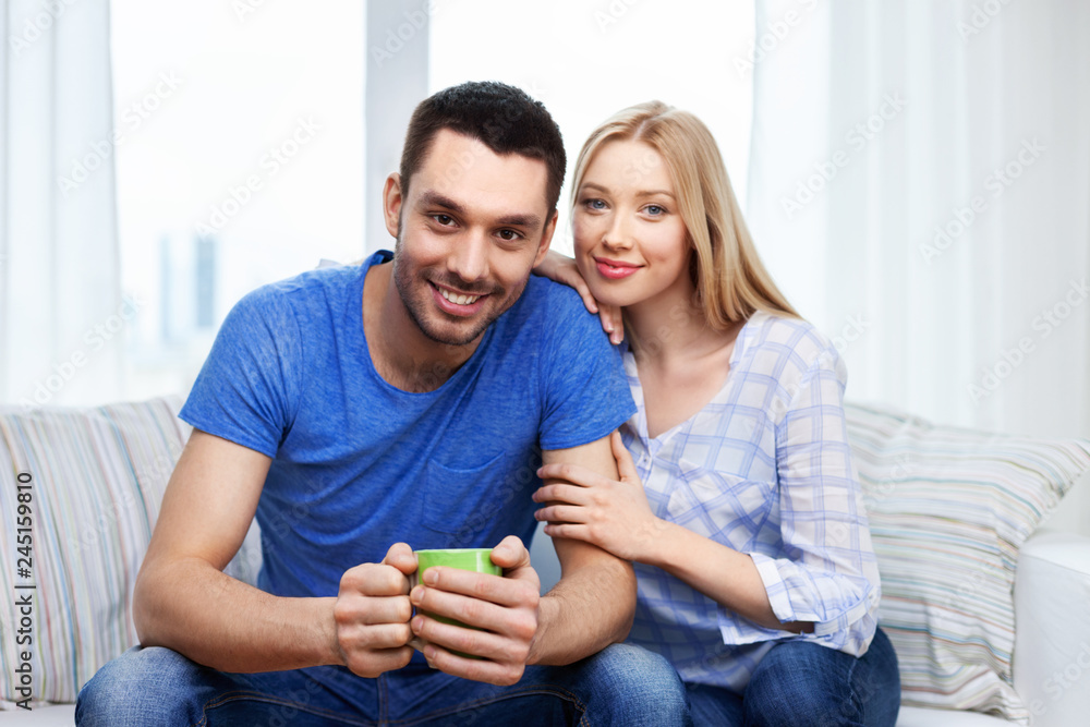 love, family and people concept - happy smiling couple sitting on sofa at home love, family and people concept - happy smiling couple sitting on sofa at home