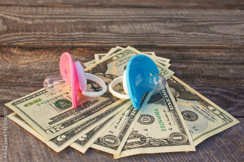 Blue and pink pacifiers on the background of money. photo