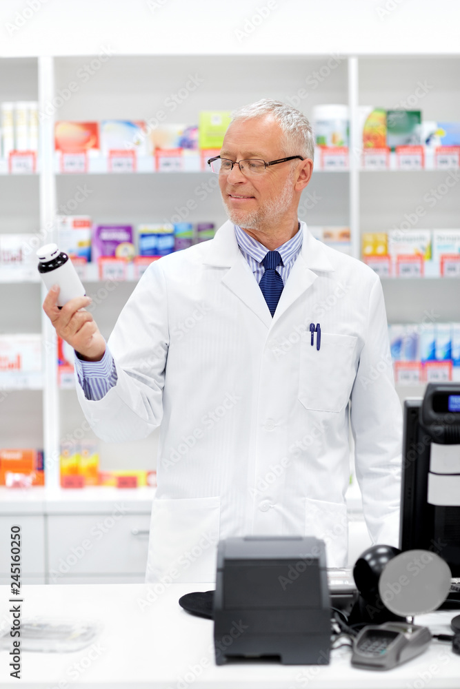 medicine, healthcare and people concept - senior apothecary with drug at pharmacy cash register