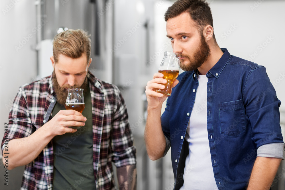 alcohol production, manufacture, business and people concept - men drinking and testing craft beer at brewery