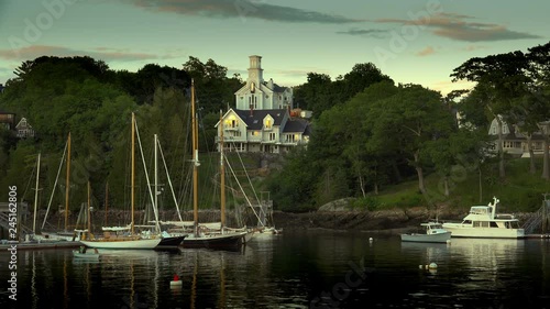 Sailboats and fishing boats in a quaint New England harbor at sunset with home looking down on the water. Nice image form real estate sales. photo