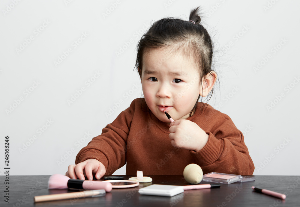 Beautiful cute Asian little girl playing makeup game Beautiful cute Asian little girl playing makeup game