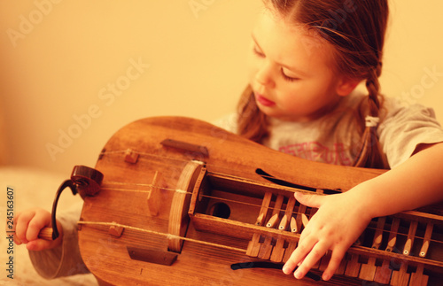 Foto little girl learn to play hurdy-gurdy