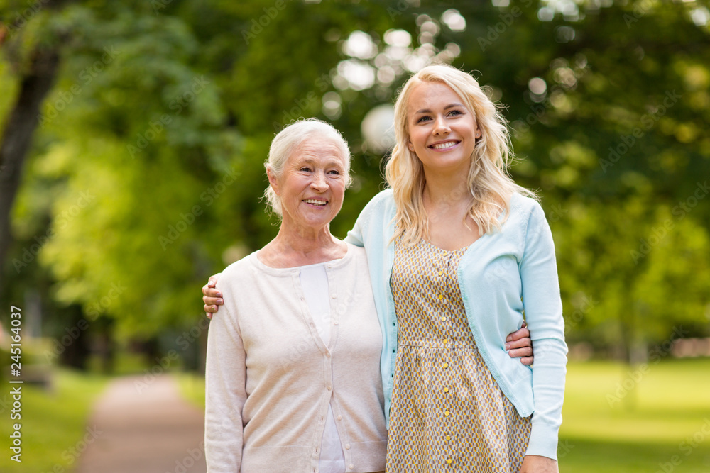 family, generation and people concept - happy smiling young daughter with senior mother hugging at summer park family, generation and people concept - happy smiling young daughter with senior mother hugging at summer park