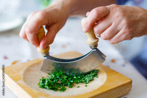 A woman shreds parsley on a wooden cutting board in the kitchen photo