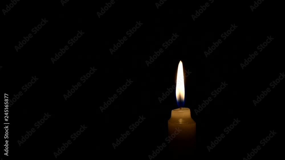 Light candle burning brightly in the black background. The concept of mourning, grief or sorrow. Located on the right side of the shot. Instantly extinguished by a strong gust of wind. Light candle burning brightly in the black background. The concept of mourning, grief or sorrow. Located on the right side of the shot. Instantly extinguished by a strong gust of wind.