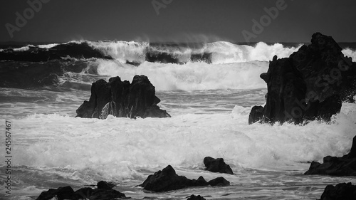 Waves crash along the black...