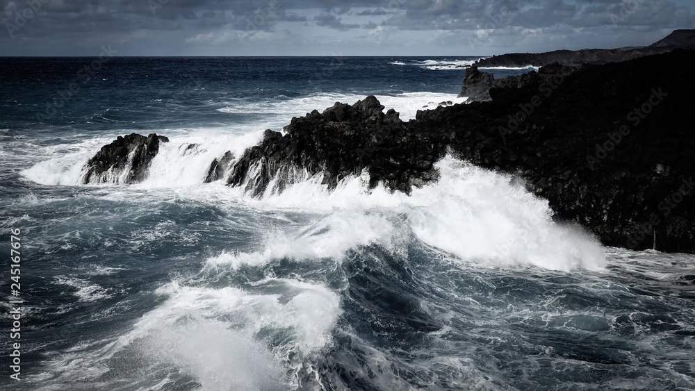 Waves crash along the black lava rock cliffs. Lanzarote, Canary Islands. Waves crash along the black lava rock cliffs. Lanzarote, Canary Islands.