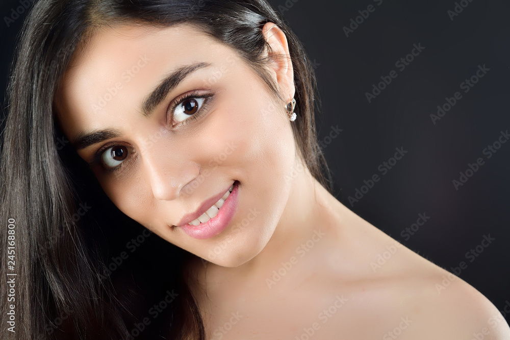 Obraz premium Portrait of a beautiful girl who stands in the studio and smiles at the camera in the studio on a black background
