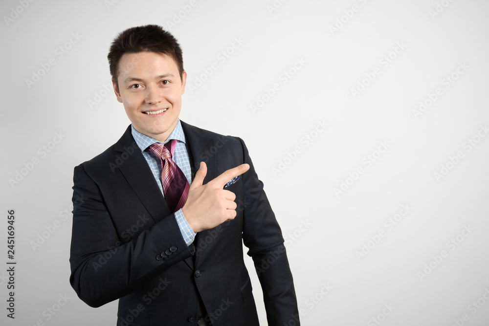 Adult businessman in suit on gray background points his finger, smiling. Adult businessman in suit on gray background points his finger, smiling.