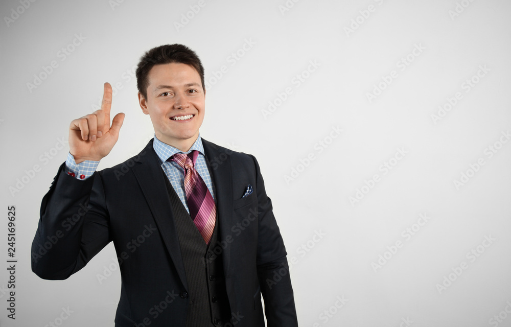 Adult businessman in suit on gray background points his finger, smiling. Adult businessman in suit on gray background points his finger, smiling.