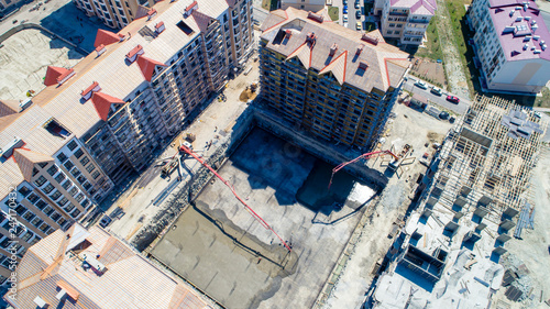 the casting of the concrete Foundation of a house. Bird's-eye view. Two concrete pumps feed the solution into an earthen pit, where workers level the concrete. Concrete is transported in a concrete mi © Александр Трихонюк