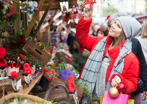 Young female near counter with xmas gifts on street market