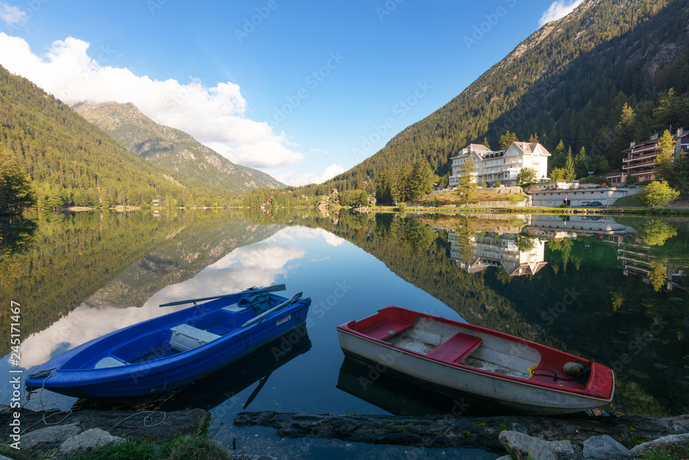 Landscapes of the Swiss high mountain lake full of trout, with boats on the beach and vacationers around.